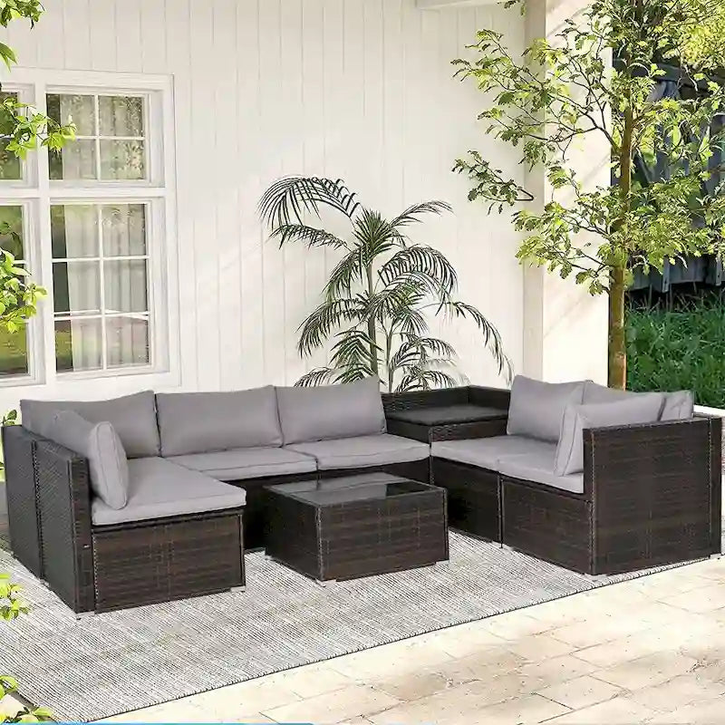 Ensemble de mobilier de jardin en rotin marron et gris 8 pièces comprenant 6 canapés, 1 table basse, un coffre de rangement et des coussins.